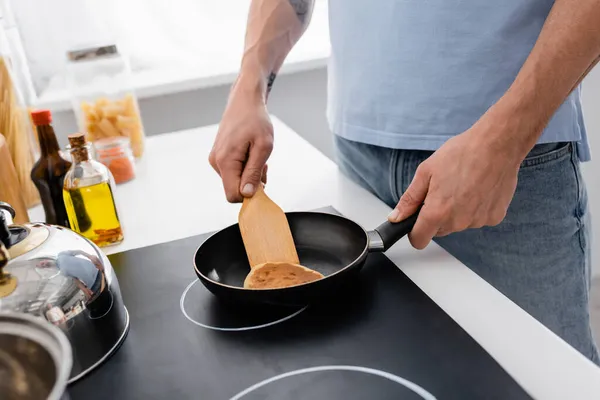 Vista recortada del hombre con espátula panqueque de cocina en la cocina — Stock Photo