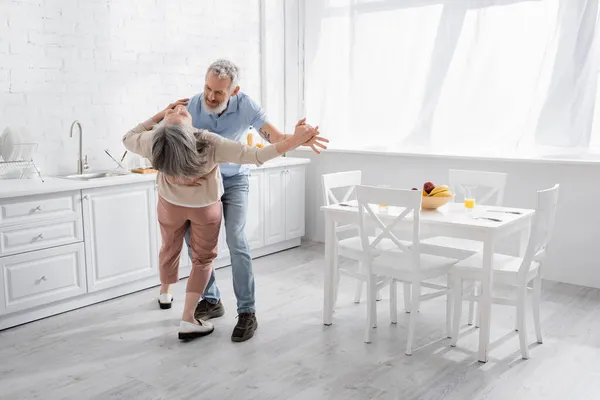 Homme dansant avec femme mature dans la cuisine — Photo de stock