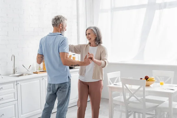 Donna che tiene per mano il marito tatuato in cucina. Traduzione: 