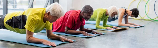 Allenamento multietnico di anziani su tappeti fitness in palestra, banner — Foto stock