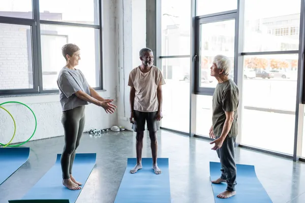 Multiethnische Senioren stehen im Sportzentrum auf Fitnessmatten — Stockfoto