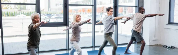 Personas mayores interraciales de pie en yoga posan en centro deportivo, pancarta - foto de stock