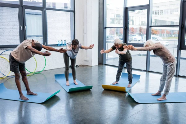 Gente multiétnica descalza practicando yoga sobre esteras en un centro deportivo - foto de stock