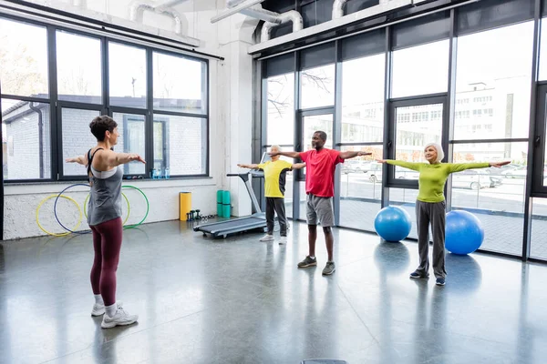 Entrenador trabajando con personas mayores multiétnicas en un centro deportivo - foto de stock