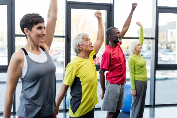 Gris pelo asiático hombre formación cerca multiétnico personas en gimnasio - foto de stock