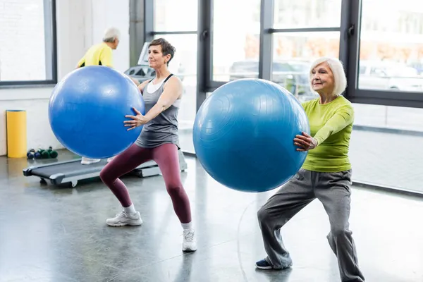 Desportistas idosas exercitam-se com bolas de fitness no ginásio — Fotografia de Stock