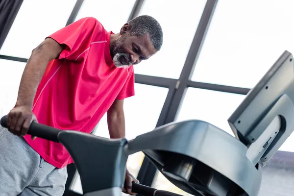 Низький кут зору старшого афроамериканця тренування на біговій доріжці в спортзалі — стокове фото