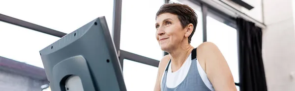 Niedriger Blickwinkel auf ältere Sportlerinnen beim Training auf dem Laufband im Fitnessstudio, Banner — Stockfoto