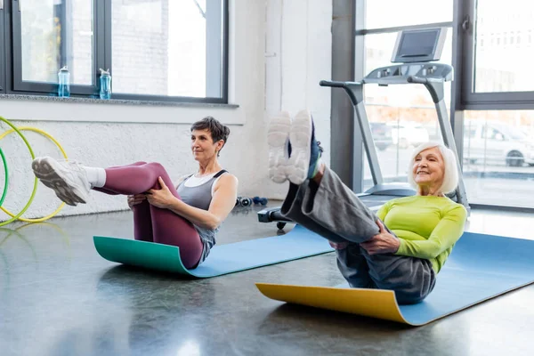 Entrenamiento de deportistas senior en colchonetas de fitness en gimnasio - foto de stock