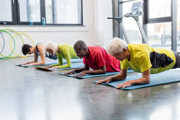 Desportista asiático em pé na prancha no tapete de fitness no ginásio — Fotografia de Stock