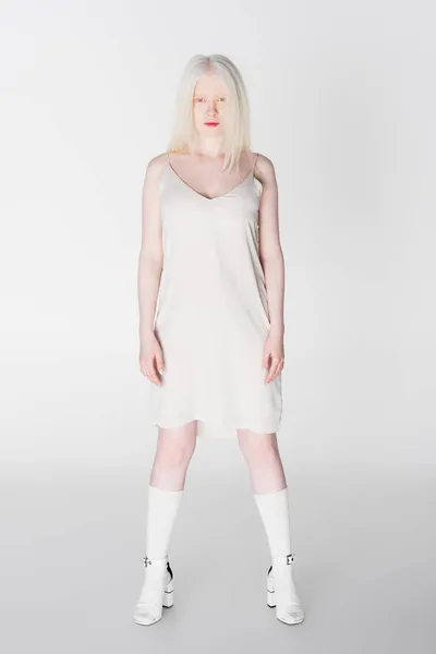 Longitud completa del modelo albino en sandalias de tacón y vestido sobre fondo blanco - foto de stock