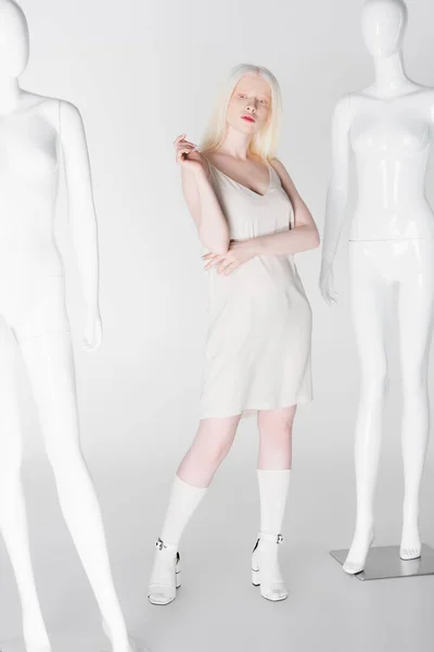 Stylish albino woman posing near mannequins on white background — Stock Photo