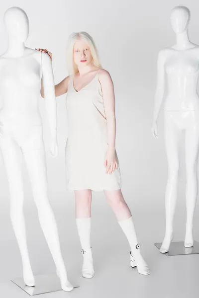 Full length of albino model touching mannequin on white background — Stock Photo