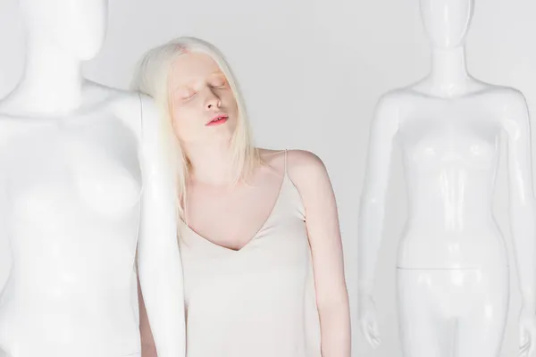 Jeune femme albinos avec les yeux fermés debout près du mannequin isolé sur blanc — Photo de stock