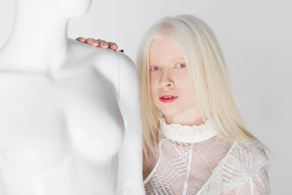 Blonde woman in blouse looking at camera near mannequin isolated on white — Stock Photo