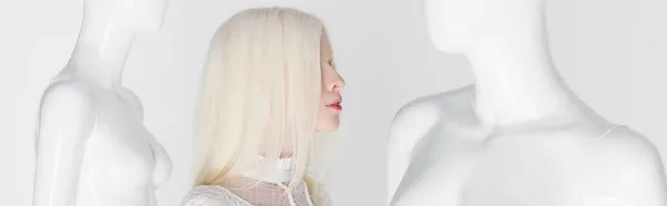 Vue latérale de femme albinos debout entre mannequins isolés sur blanc, bannière — Photo de stock