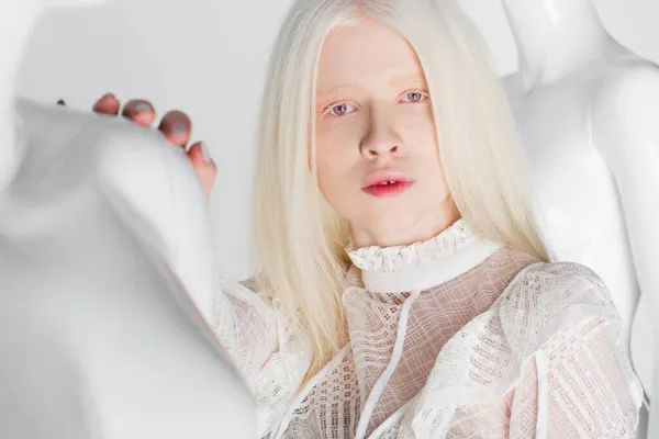 Mujer albina bastante de pie cerca de maniquí borroso aislado en blanco - foto de stock