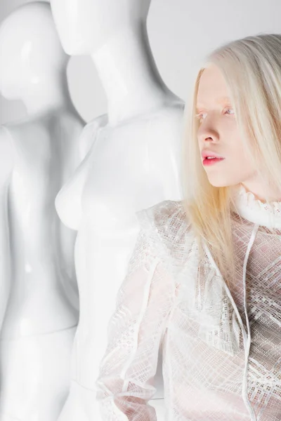 Досить альбінової жінки в блузці, що стоїть біля манекенів ізольовано на білому — стокове фото