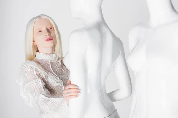 Bastante albino y rubia mujer sosteniendo maniquí aislado en blanco - foto de stock