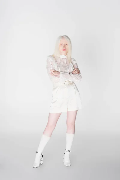 Comprimento total de albino elegante e mulher loira com braços cruzados no fundo branco — Fotografia de Stock