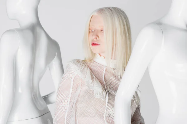 Modelo albino en blusa de pie cerca de maniquíes aislados en blanco - foto de stock