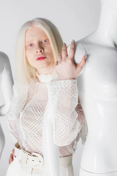 Stylish albino woman touching mannequin and looking at camera isolated on white — Stock Photo