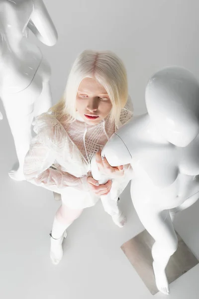 Overhead view of albino woman touching mannequin on white background — Stock Photo