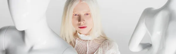 Blonde albinos femme debout entre mannequins isolé sur blanc, bannière — Photo de stock