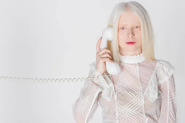 Mujer albina hablando por teléfono y mirando a la cámara aislada en blanco - foto de stock