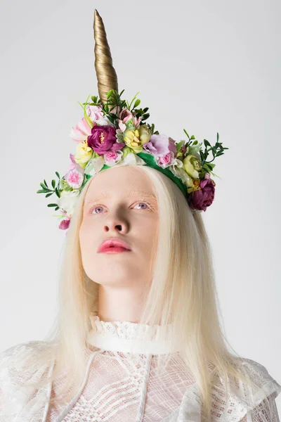 Retrato de mujer albina y rubia en corona floral con cuerno aislado en gris - foto de stock