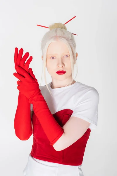 Mujer albina bonita en guantes rojos y palitos de pelo mirando a la cámara aislada en blanco - foto de stock