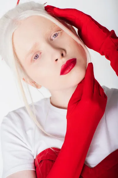 Modelo albino y rubio en guantes rojos posando aislados sobre blanco - foto de stock