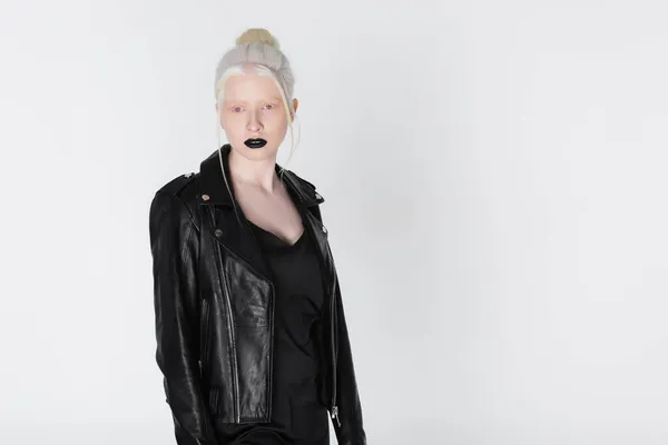 Модна альбіносова жінка в шкіряній куртці з чорними губами позує ізольовано на білому — стокове фото