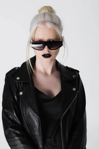 Stylish albino woman in sunglasses and leather jacket looking at camera isolated on white — Stock Photo
