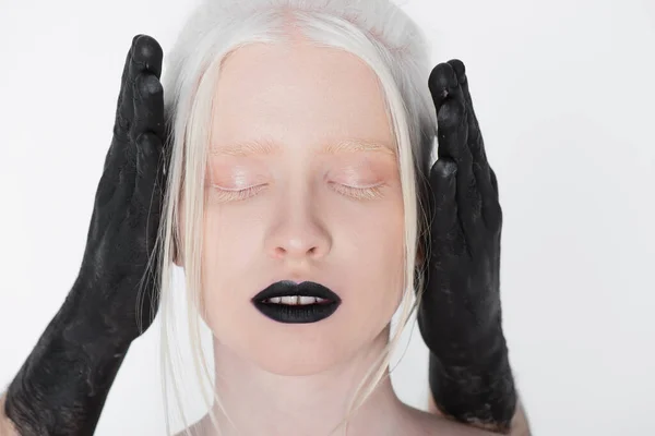 Male hands in black paint covering ears of albino model isolated on white — Stock Photo