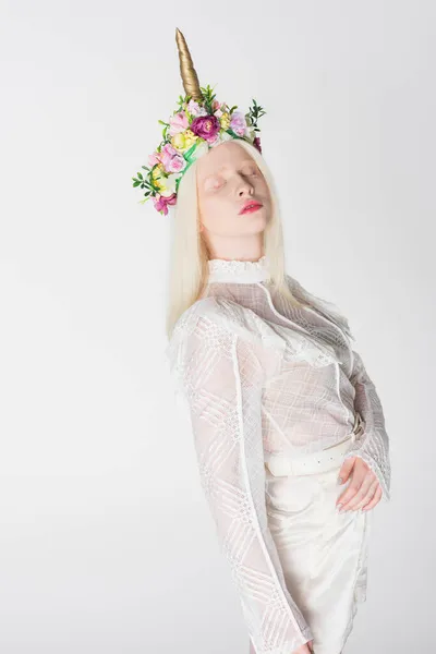 Jeune femme albinos en chemisier et couronne de fleurs et corne posant isolée sur blanc — Photo de stock