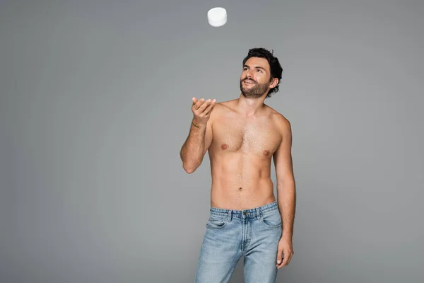 Homem feliz e sem camisa jogando recipiente com creme cosmético isolado em cinza — Fotografia de Stock