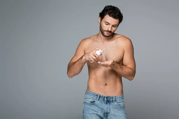 Homem barbudo e sem camisa em jeans segurando limpador de espuma isolado em cinza — Fotografia de Stock