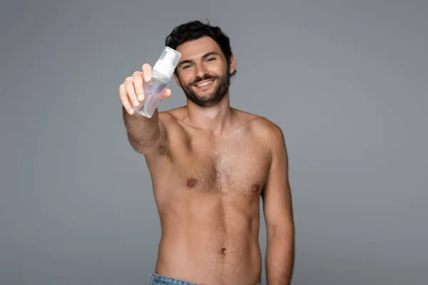 Homem feliz e sem camisa segurando limpador de espuma isolado em cinza — Fotografia de Stock