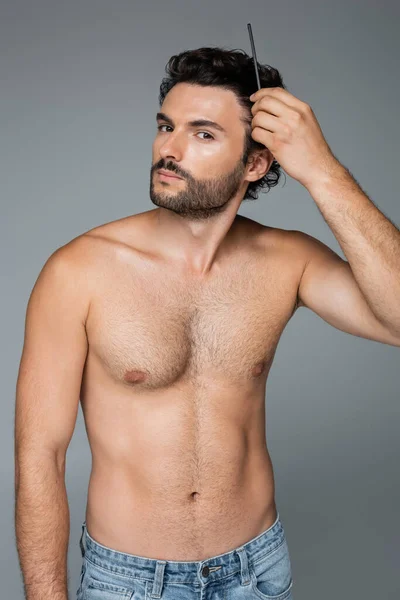 Hemdloser Mann bürstet welliges Haar mit Kamm isoliert auf grau — Stockfoto