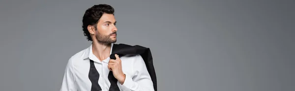 Hombre barbudo en camisa blanca sosteniendo chaqueta aislado en gris, bandera - foto de stock