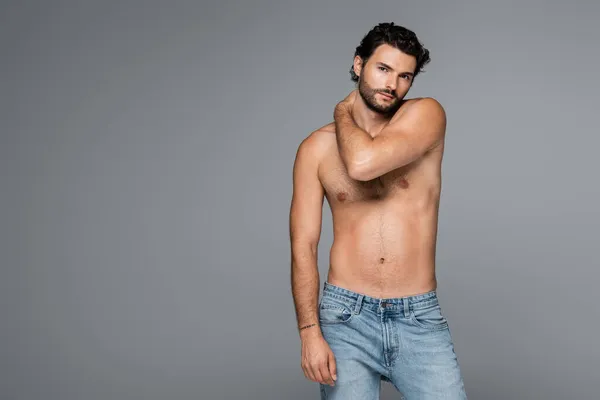 Homme beau et musclé en jeans regardant la caméra isolée sur gris — Photo de stock