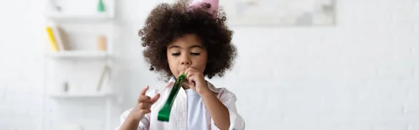 Lockiges afrikanisch-amerikanisches Kind bläst in Partyhorn, Banner — Stockfoto