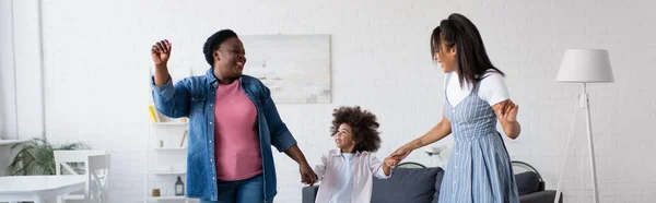 Aufgeregtes afrikanisch-amerikanisches Kind tanzt im Wohnzimmer mit Mama und Oma, Banner — Stockfoto