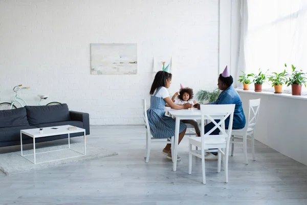 Afrikanisch-amerikanische Frauen und Mädchen in Partymützen spielen Holzklötzchen-Spiel im geräumigen Wohnzimmer — Stockfoto