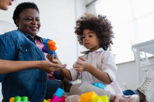 Afrikanisch-amerikanisches Kind hält Baustein beim Spielen mit Mama und Oma — Stockfoto
