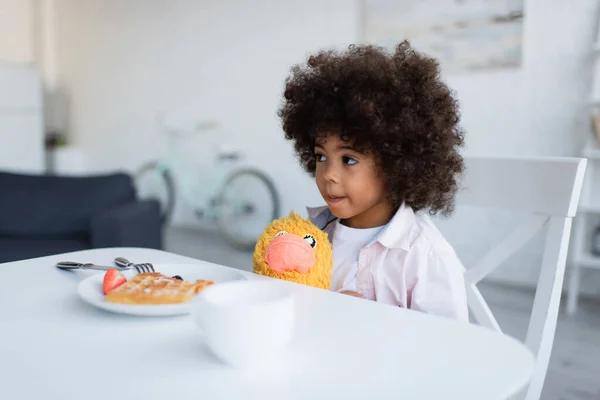 Menina americana africana sentado com brinquedo pinto perto de prato com waffle delicioso — Fotografia de Stock