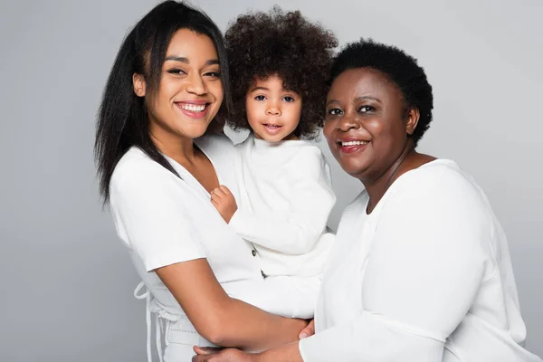 Menina americana africana em mãos de mãe feliz e vovó olhando para a câmera isolada no cinza — Fotografia de Stock