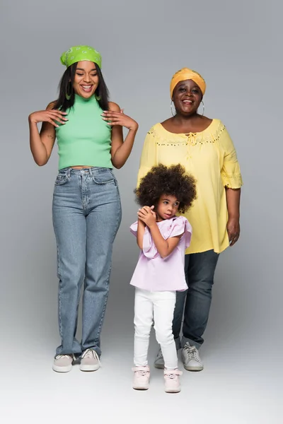 Full length view of african american women and girl in trendy clothes standing on grey — Stock Photo