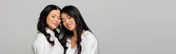 Feliz asiático madre y hija en blanco camisas sonriendo aislado en gris, bandera - foto de stock